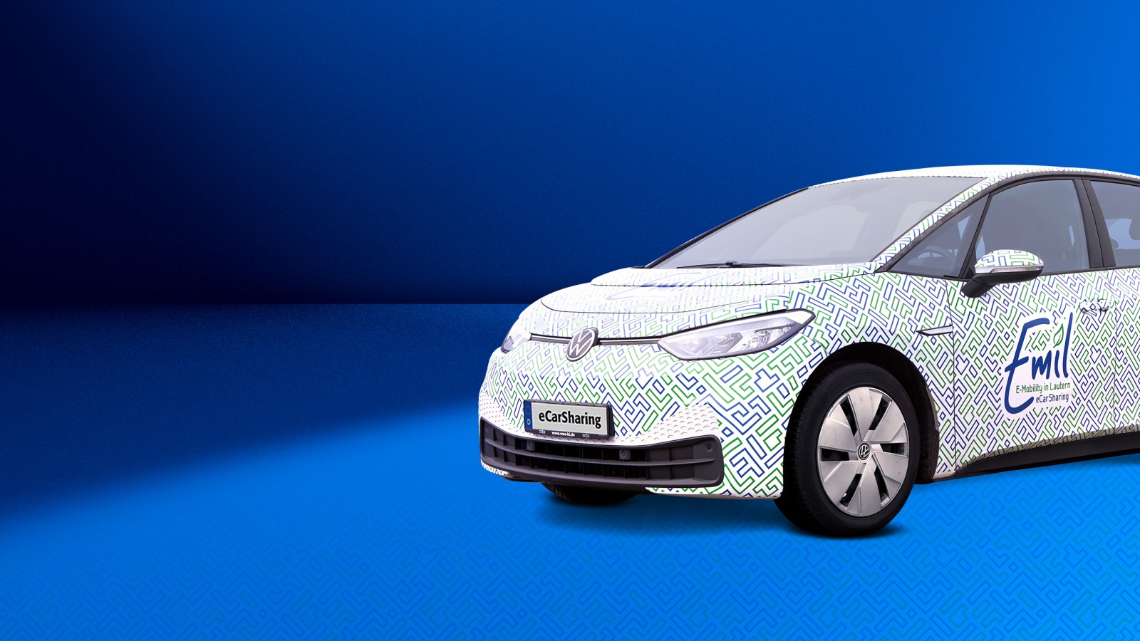 VW ID.3 mit Emil eCarSharing-Branding auf blauem Hintergrund ragt rechts bis zu Hälfte ins Bild hinein. 
